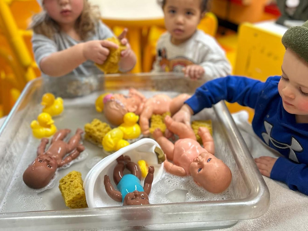 2-Year-Old Room - teacher with 2-year-olds on carpet at Robins Nest Learning Center