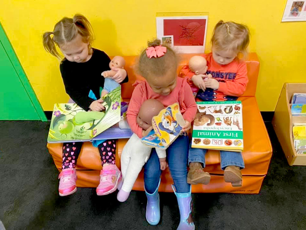 2-Year-Old Room - 2-year-old girls reading books at Robins Nest Learning Center