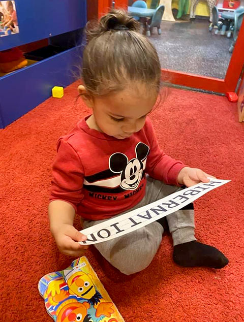 2-Year-Old Room - girl reading a book at Robins Nest Learning Center