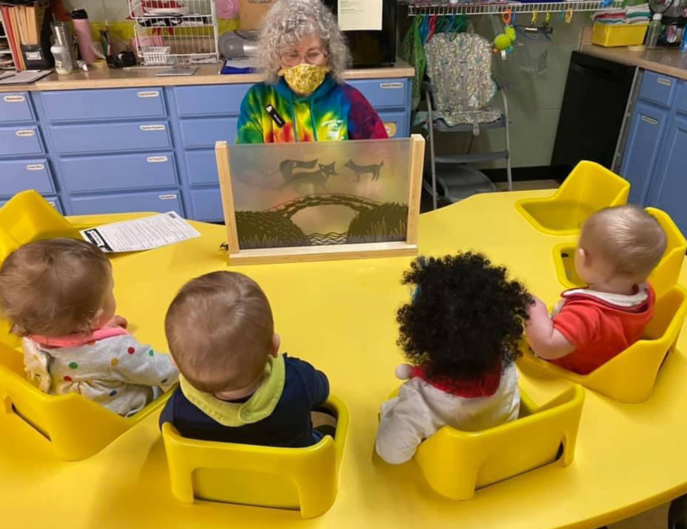 Teacher playing with babies at Robins Nest Learning Center