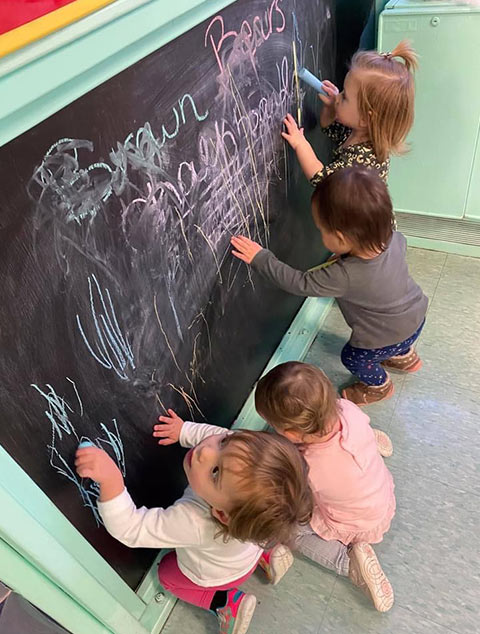 Infants playing with chalk at Robins Nest Learning Center at Robins Nest Learning Center